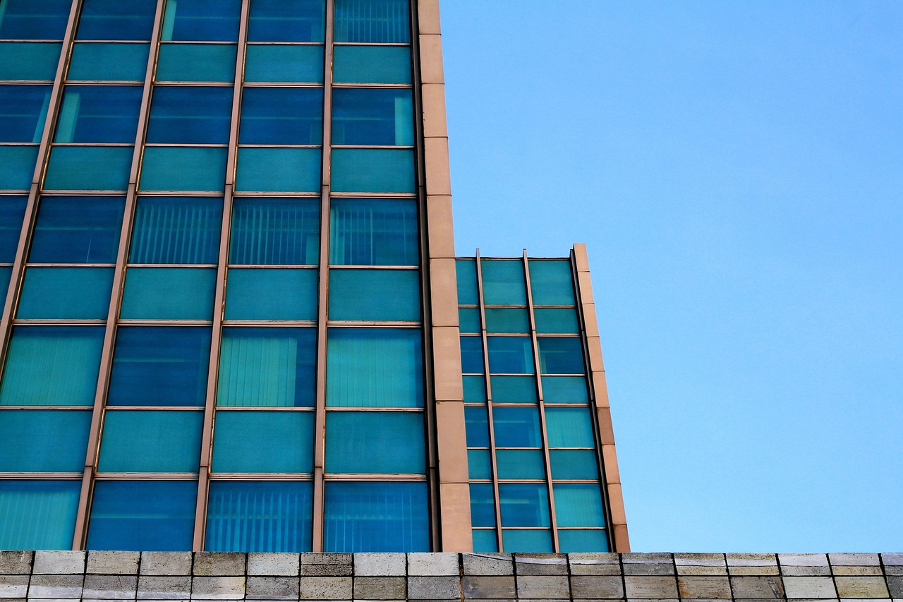 A modernist glass and stone office facade seen from below